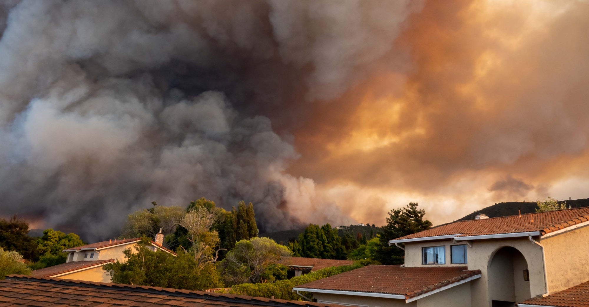 wildfire burning behind houses