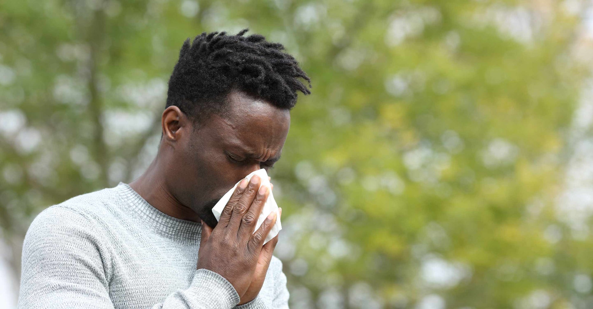 Man sneezing standing otuside